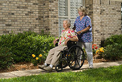 maison de retraite : infirmière poussant un résidant sur son fauteuil roulant